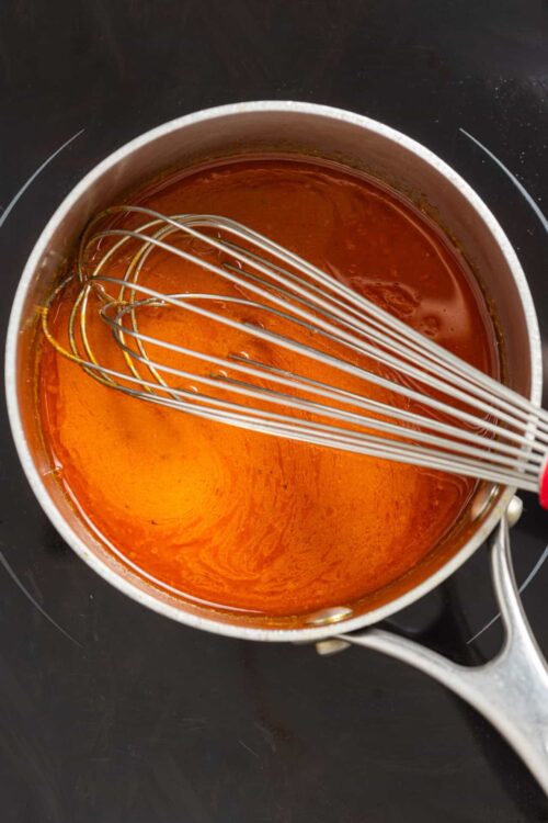 Silicone pot with caramel sauce and a whisk.