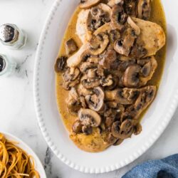 Portobello mushroom chicken with mushroom sauce on a white platter.