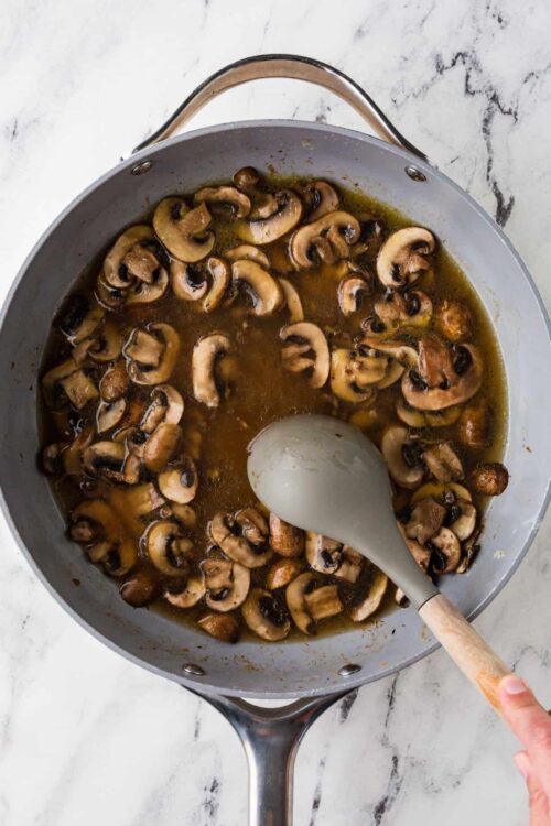 Sautéed mushrooms in a skillet with butter and herbs.