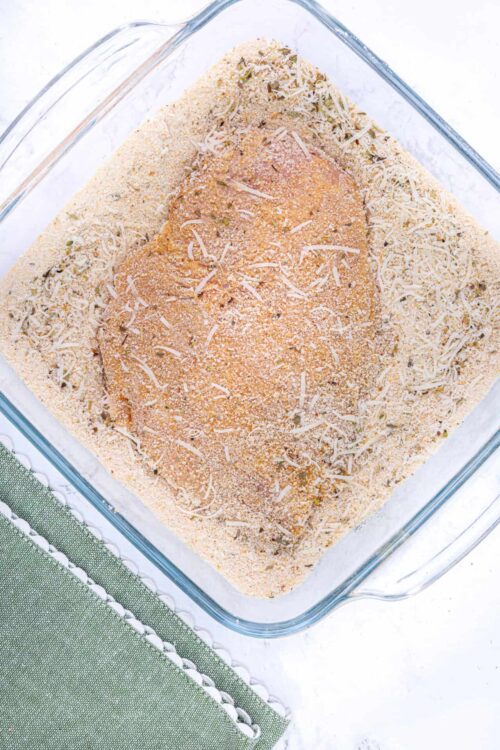 Golden baked chicken breast coated with bread crumbs in a glass baking dish.