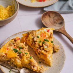 Savory breakfast casserole with sausage, eggs, cheese, and vegetables on a rustic plate.