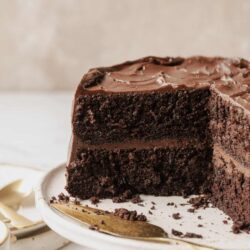 Decadent homemade chocolate layer cake with rich frosting on a white cake stand.