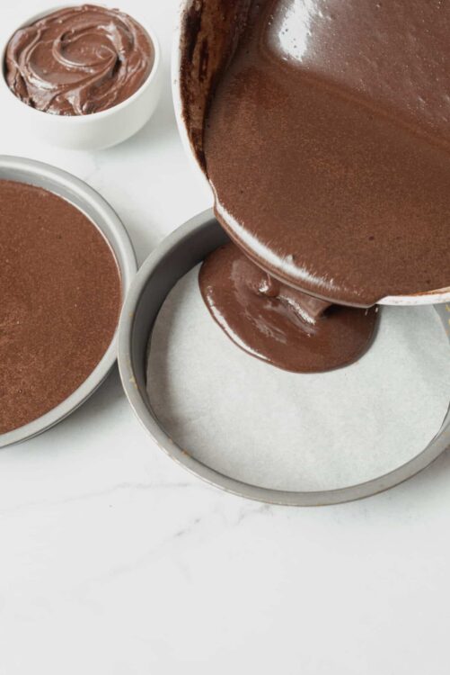 Rich homemade chocolate ganache being poured into a baking pan for dessert preparation.