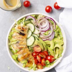 Fresh veggie salad with grilled chicken, cherry tomatoes, cucumbers, and red onions. Healthy summer meal.