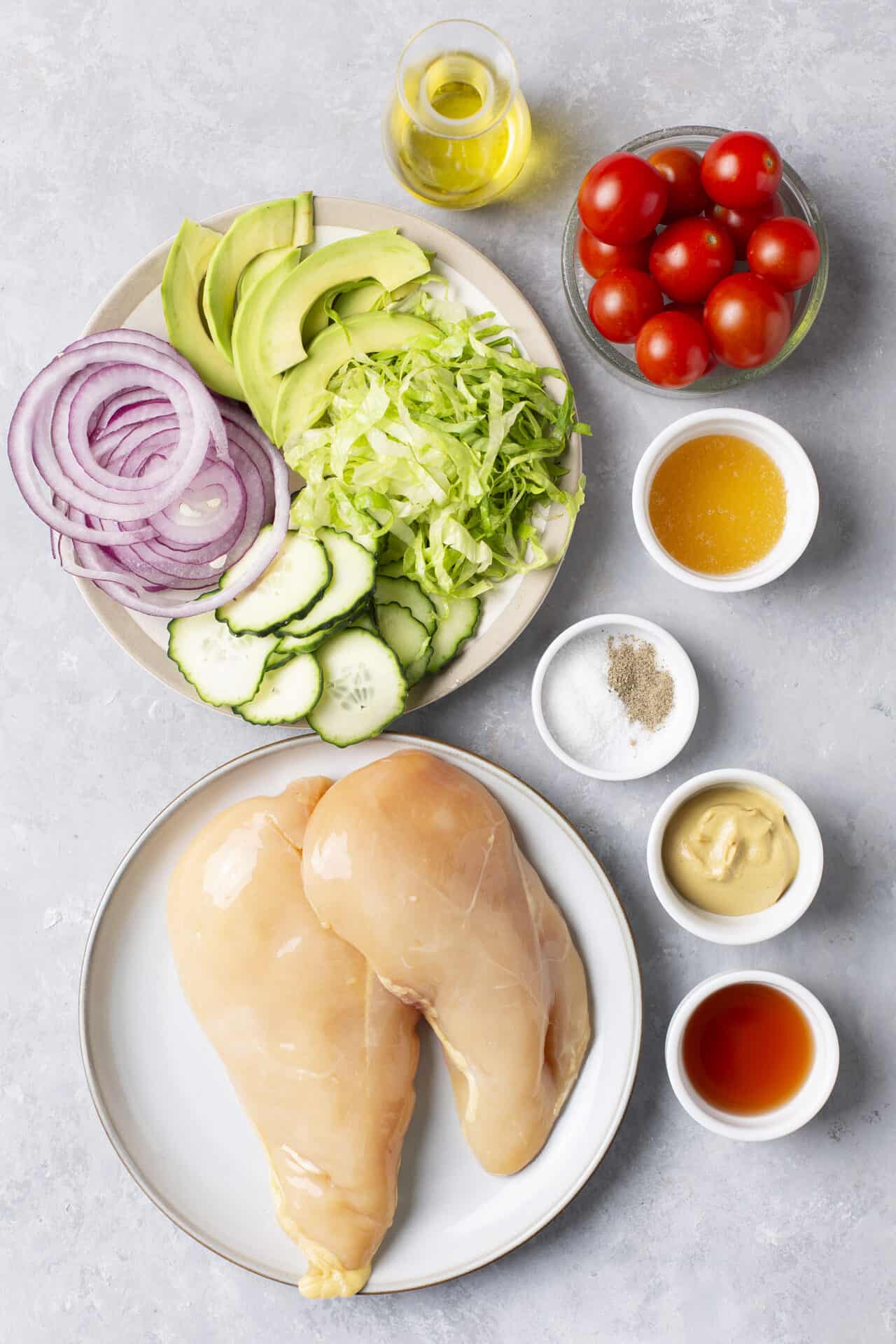 Fresh chicken breasts with chopped vegetables and seasonings for healthy recipe preparation.