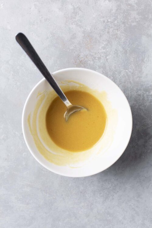Creamy butternut squash soup in white bowl topped with a spoon, perfect for fall recipes and cozy dinners.