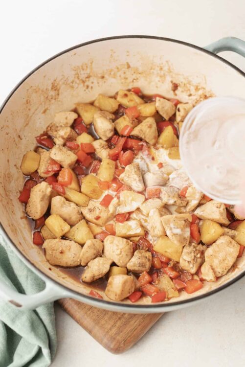 Savory chicken and vegetable skillet in a white enameled cast iron skillet.