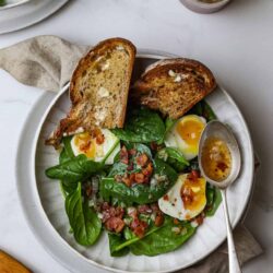 Crispy bread with soft boiled eggs and fresh spinach salad.