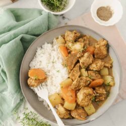 Savory chicken and vegetables served with white rice on a neutral bowl.