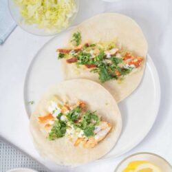 Fresh chicken tacos with cilantro, lime, and shredded cheese on soft flour tortillas.
