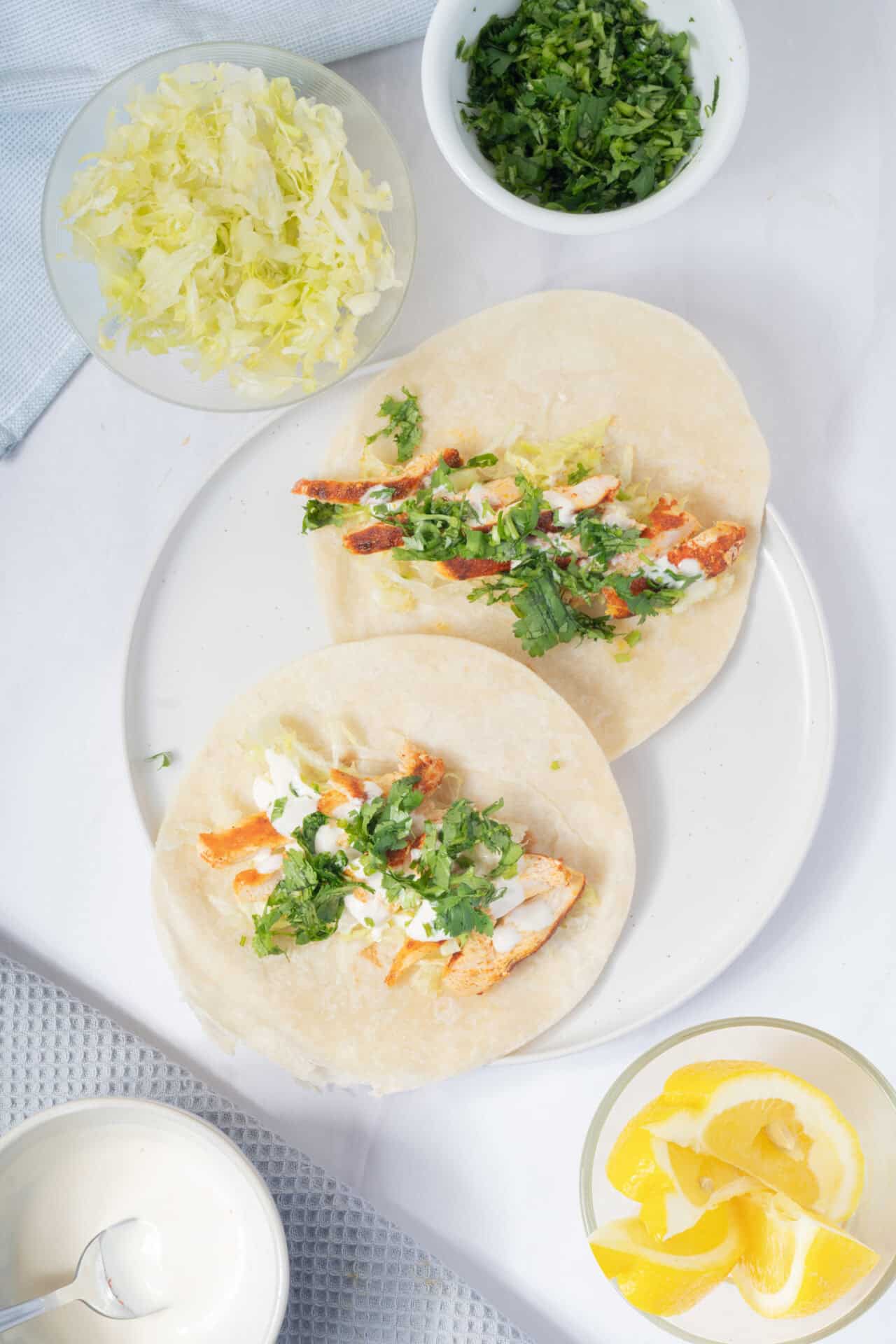 Fresh chicken tacos with cilantro, lime, and shredded cheese on soft flour tortillas.