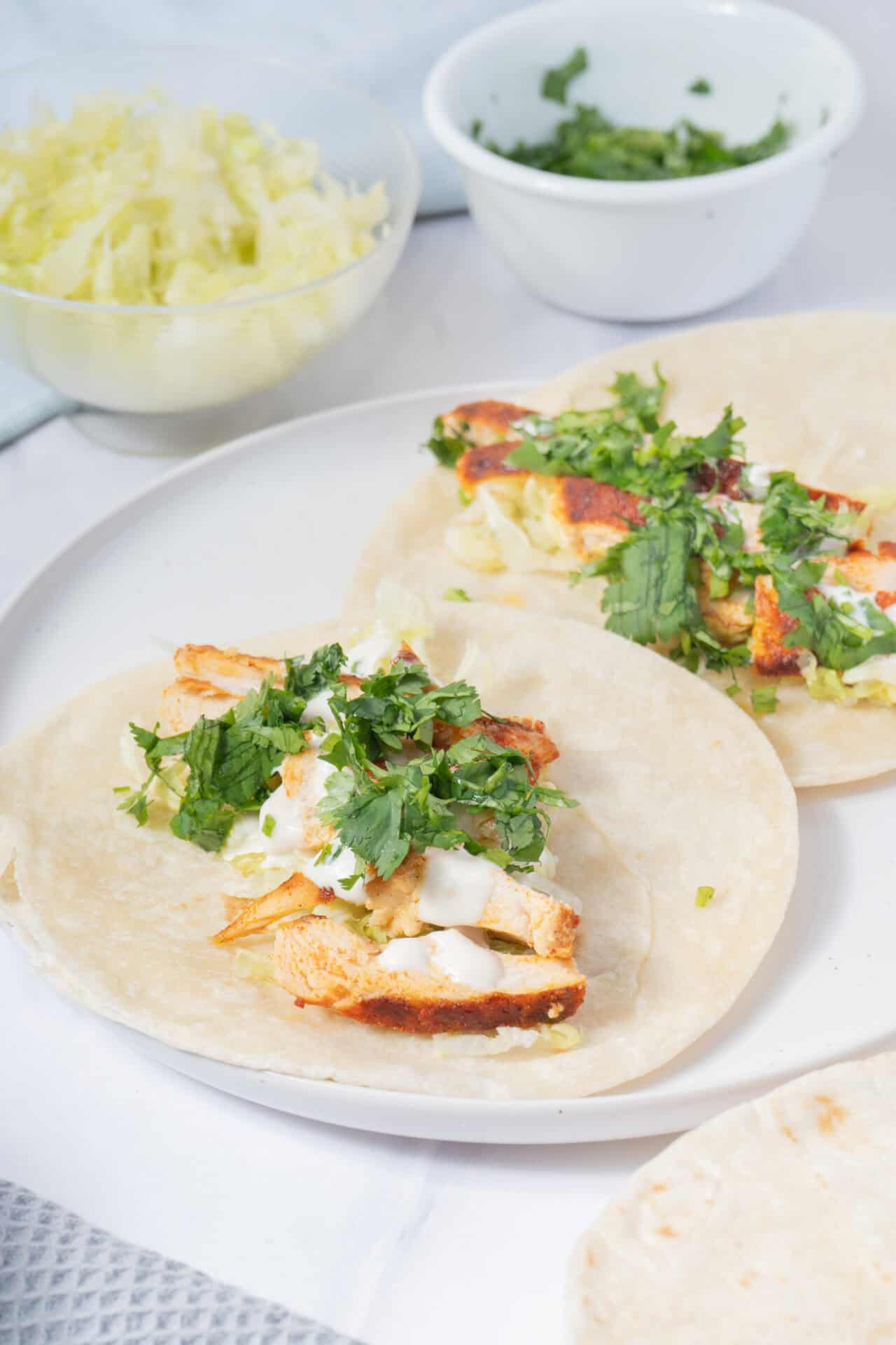 Grilled chicken tacos with fresh cilantro and creamy sauce on soft flour tortillas.