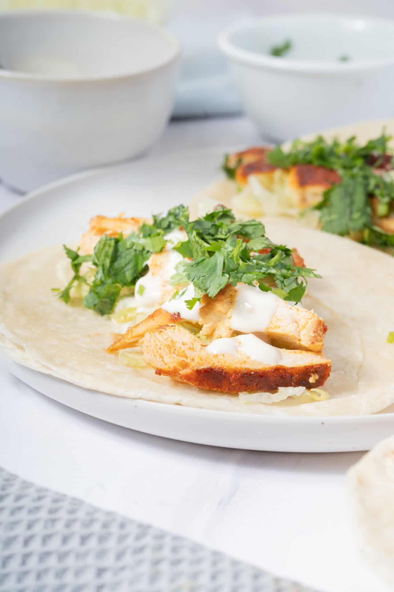 Grilled chicken fajita taco with fresh cilantro and creamy sauce on a soft tortilla.