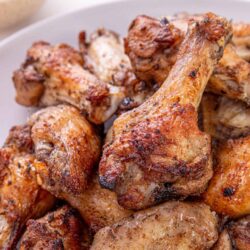 Crispy seasoned baked chicken drumsticks and thighs on white plate.