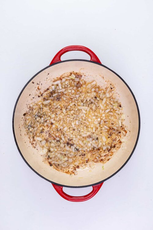 Sautéed onions and spices in a red cast iron skillet.