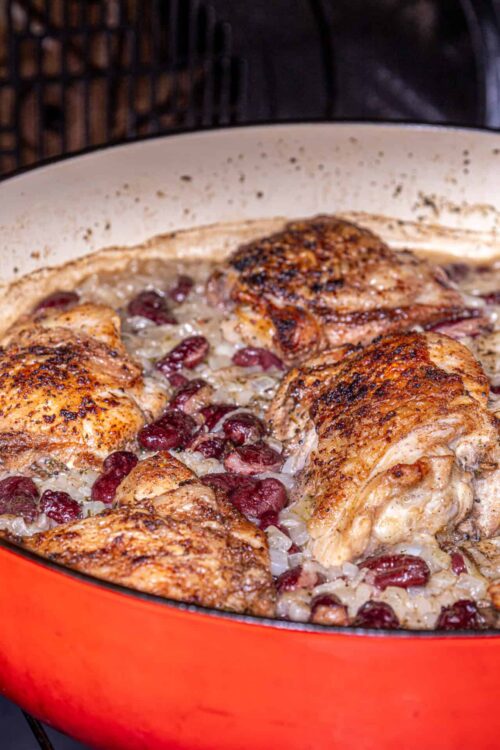 Crispy roasted chicken with onions and cranberries in a Dutch oven.