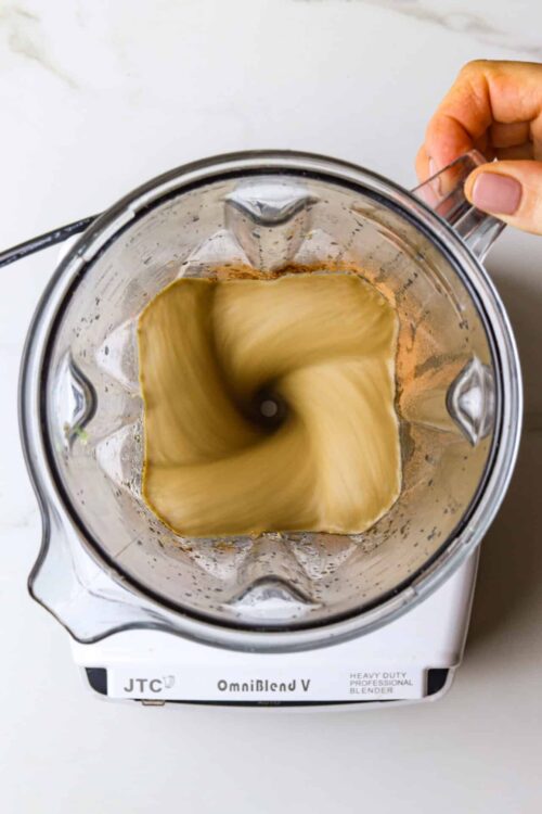 Blended coffee being prepared in a blender with a whirl effect.