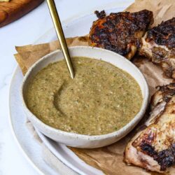 Creamy herb dipping sauce served with grilled chicken and crispy fries on a white plate.
