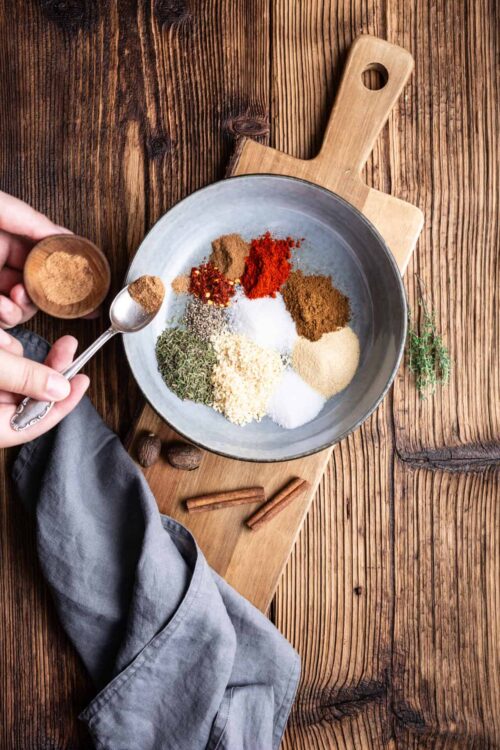 Ground spices in a metal bowl on a wooden cutting board for cooking or baking.