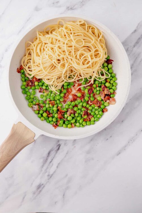 Creamy pea and bacon pasta in a white skillet, ready to serve.