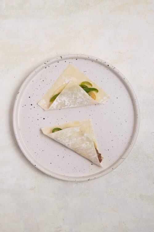 Fresh homemade beef Empanadas served on white speckled plate.