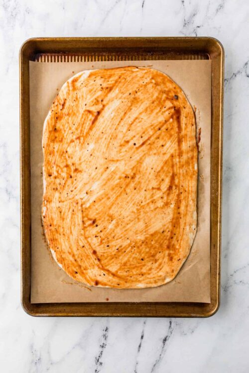 Baked chicken breast with seasoned spice rub on baking sheet.