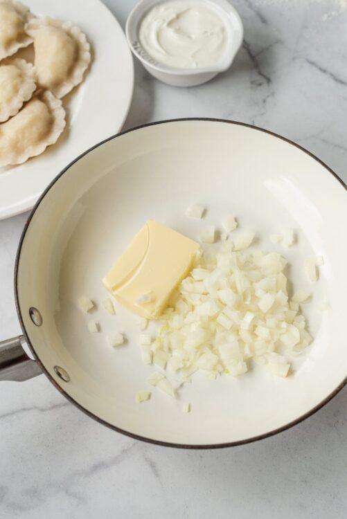 Butter and chopped onions in a skillet for cooking.