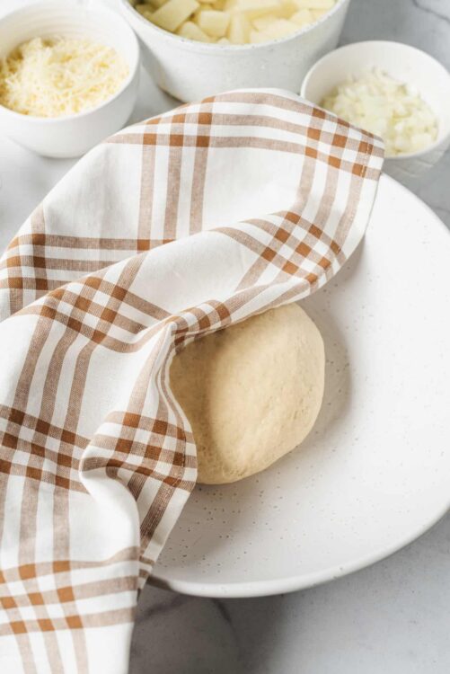 Fresh dough with a plaid kitchen towel ready for baking.