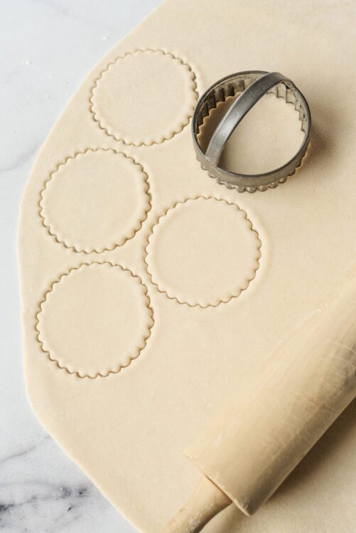 Round cookie cutter cutting out homemade cookie dough for baking.