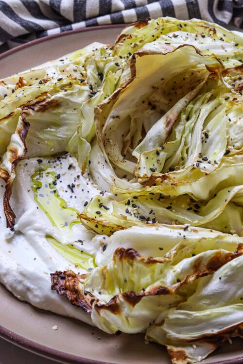 Crispy roasted cabbage wedges drizzled with olive oil and sprinkled with black sesame seeds.