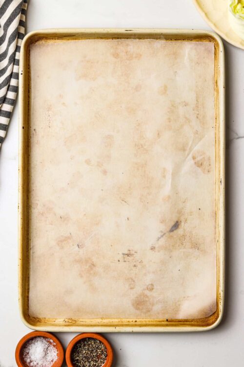 Empty baking sheet with parchment paper for baking or roasting recipes.