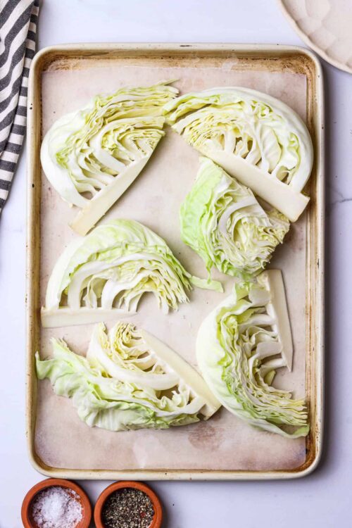 Fresh sliced Napa cabbage heads on a baking sheet for cooking or roasting.
