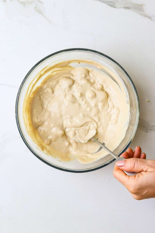 Fluffy vanilla cake batter in a glass mixing bowl on white countertop.