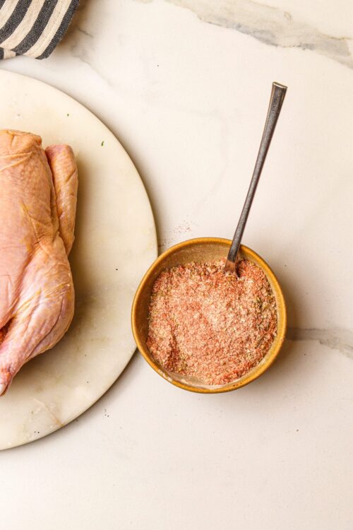 Seasoned salt mixture for roasting chicken on a marble countertop.