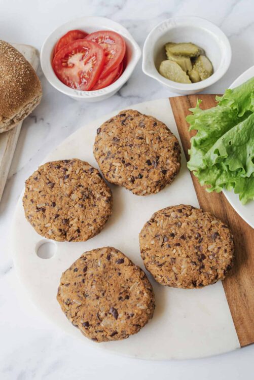Crispy black bean veggie burgers on white serving platter with fresh salad and toppings.