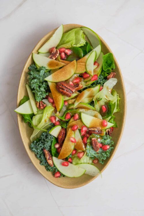 Fresh mixed green salad with pears, pecans, and pomegranate seeds. Healthy and colorful vegetarian entree or side dish.