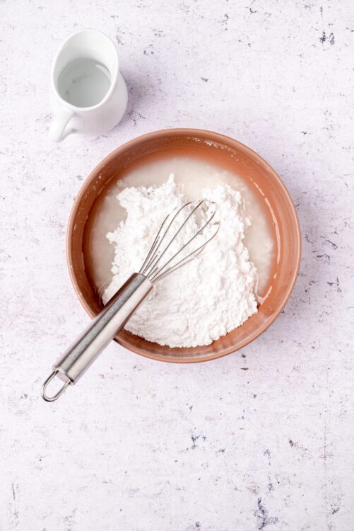 Flour being whisked with milk in a bowl for baking bread or pastries.