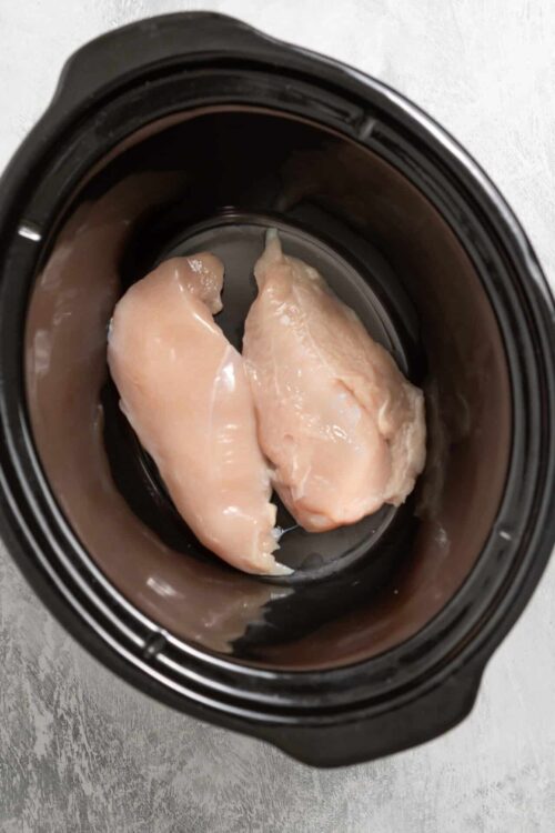 Raw chicken breasts in a slow cooker, ready for cooking or meal prep.