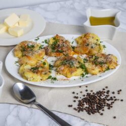 Baked potato skins topped with herbs and cheese on a white plate.