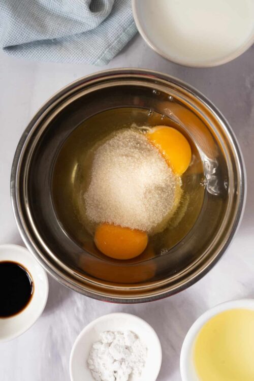 Flour eggs and sugar in a mixing bowl for baking recipe preparation.