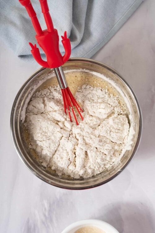 Butter and flour mixture in mixing bowl with red whisk attachment.