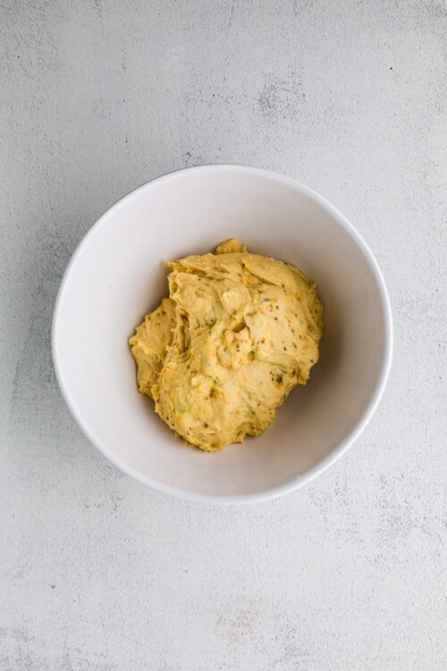 Creamy seasoned potato salad in a white bowl, served as a delicious comfort food or side dish.