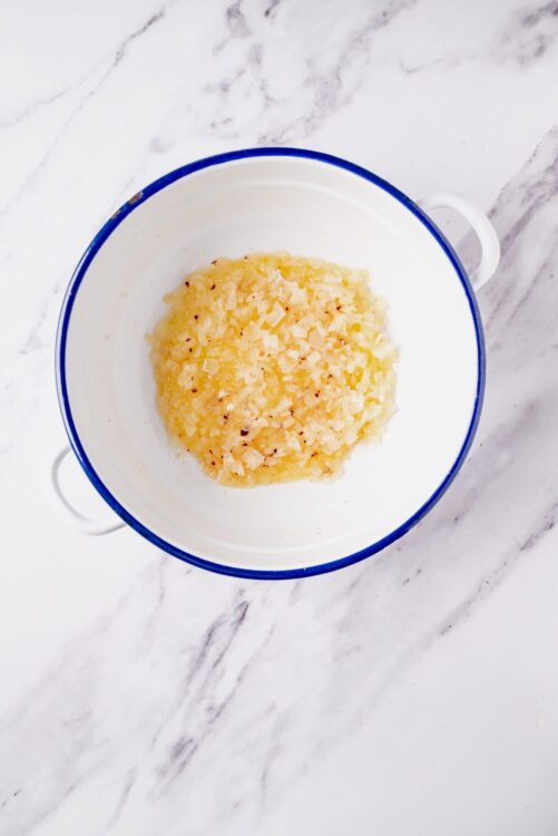 Creamed garlic in a white bowl with blue rim for cooking recipes.