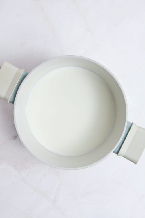 Cream milk in a white saucepan for baking or dessert recipes.