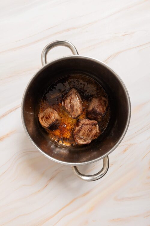 Succulent beef stew simmering in a stainless steel pot.