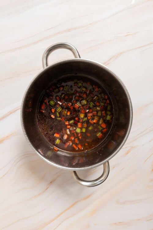 Soy sauce with chopped green onions in a small stainless steel saucepan.