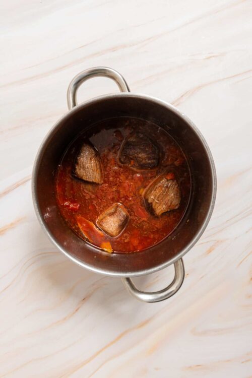 Slow cooker beef stew with chunks of tender beef in a rich tomato-based broth. Ideal for hearty, comforting meals.