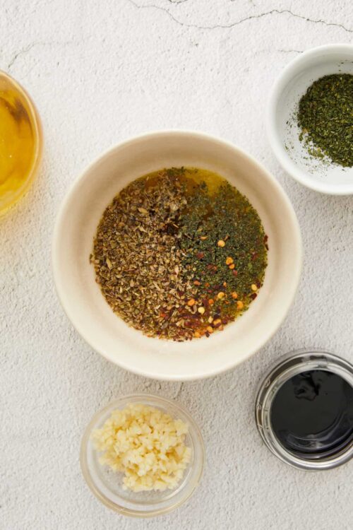 Ground herbs and spices in white bowls for cooking and seasoning.
