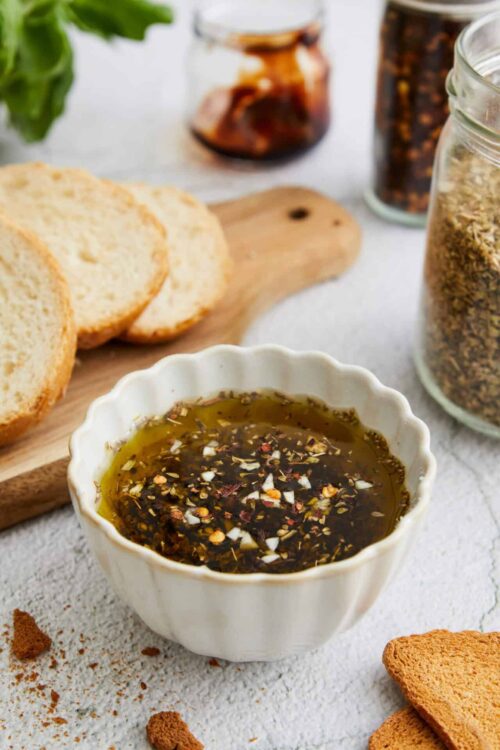 Homemade balsamic vinaigrette with garlic and herbs in a white ramekin.