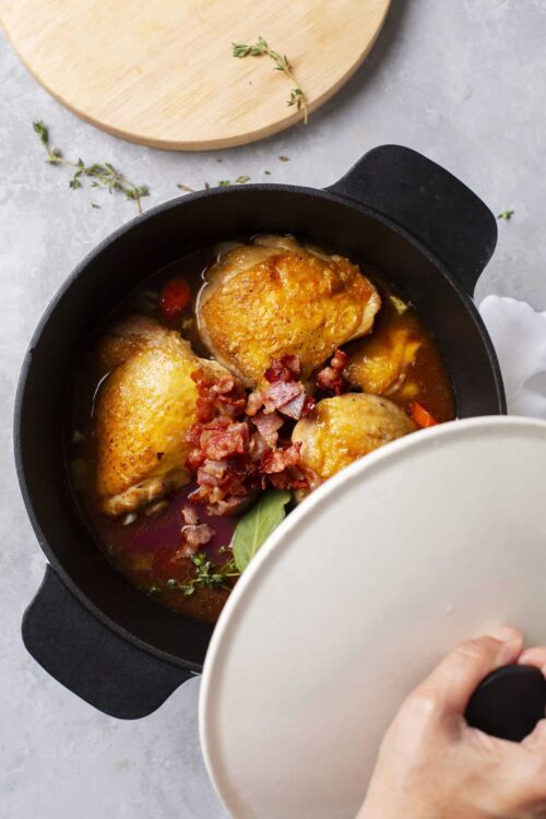 Juicy baked chicken thighs with crispy bacon and flavorful herbs in a cast iron skillet.